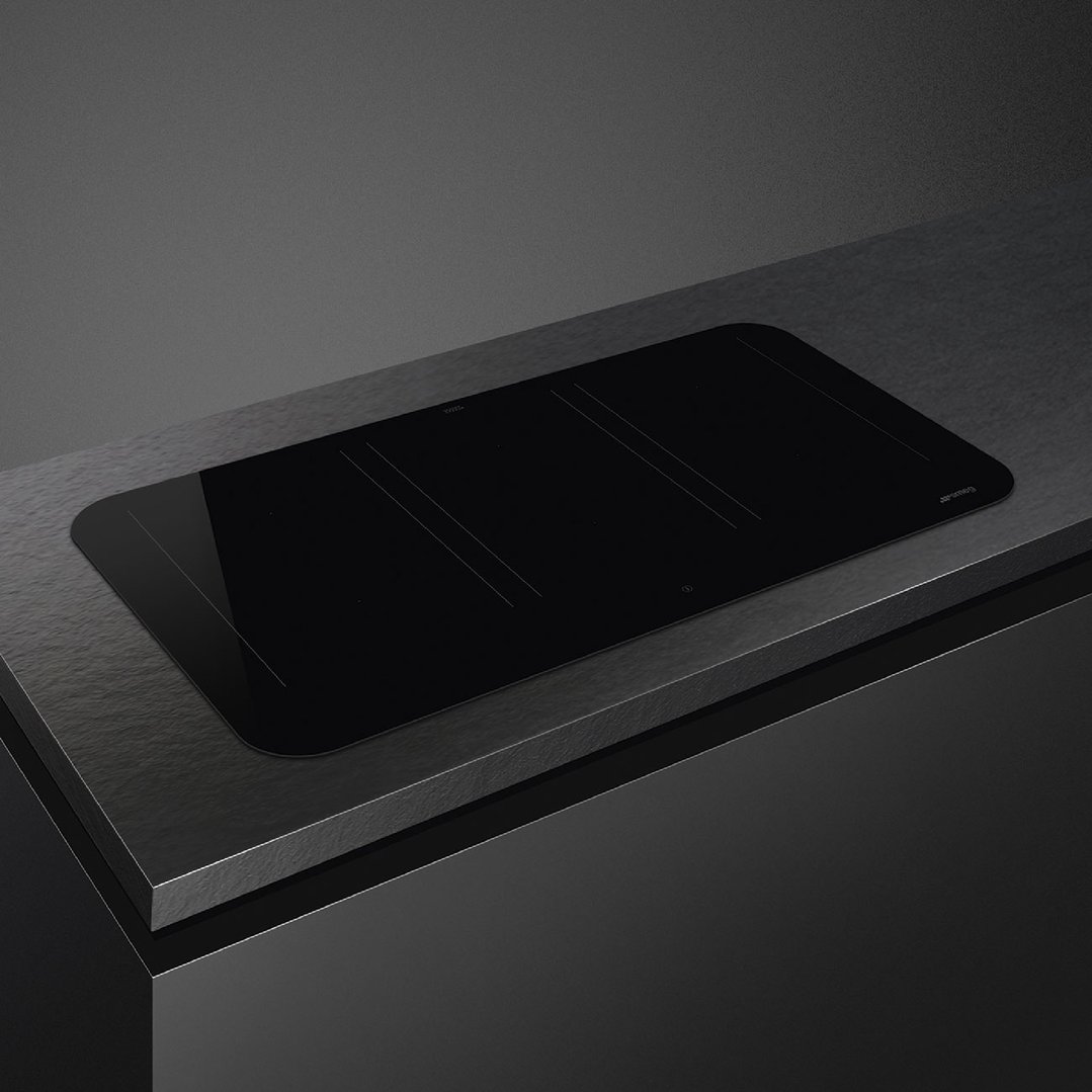 Black induction cooktop integrated into a dark countertop in a modern kitchen