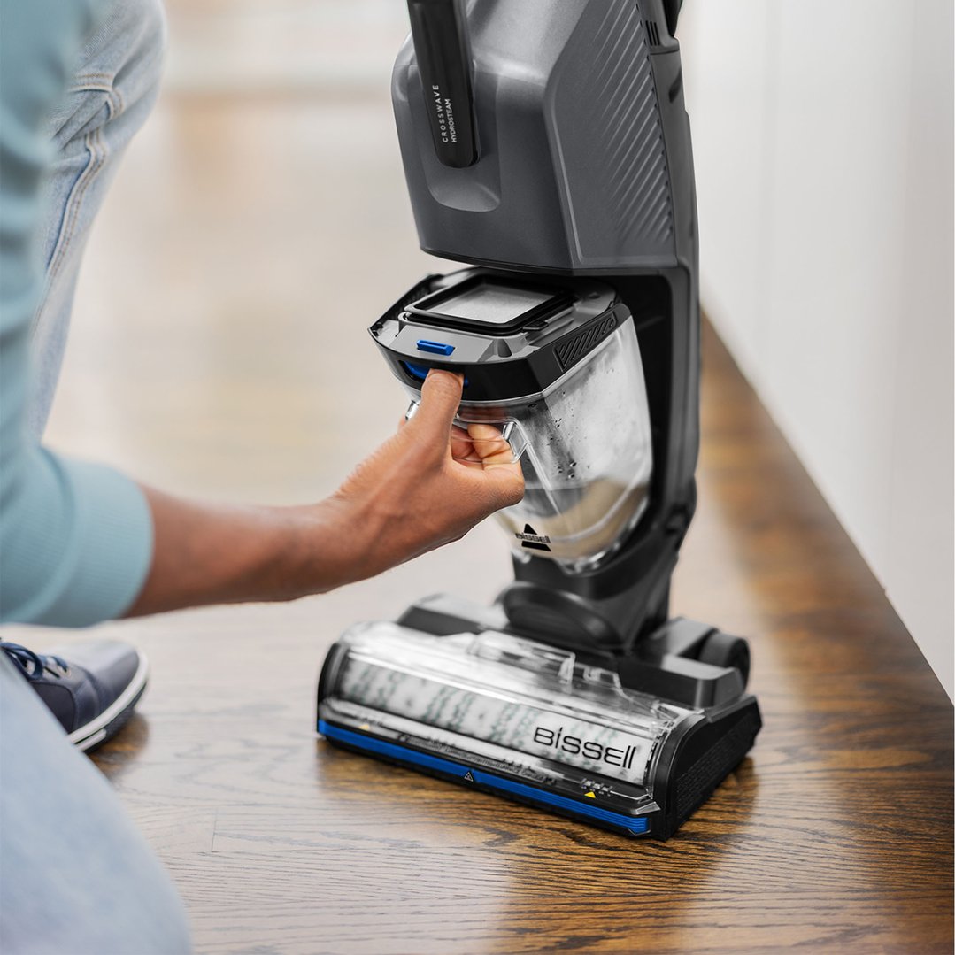 Person removing the dirty water tank from a BISSELL CrossWave HydroSteam vacuum cleaner