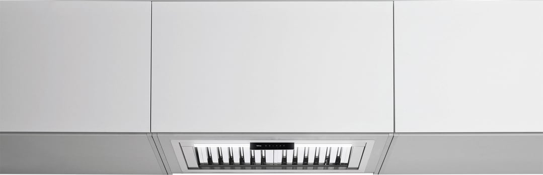 A stainless steel rangehood integrated into white kitchen cabinetry