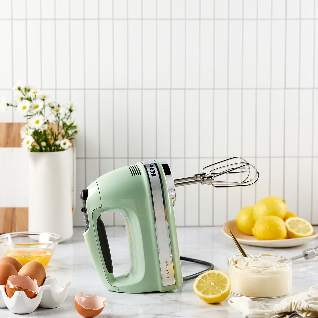 Pistachio KitchenAid 9 Speed Hand Mixer on a marble counter with baking ingredients