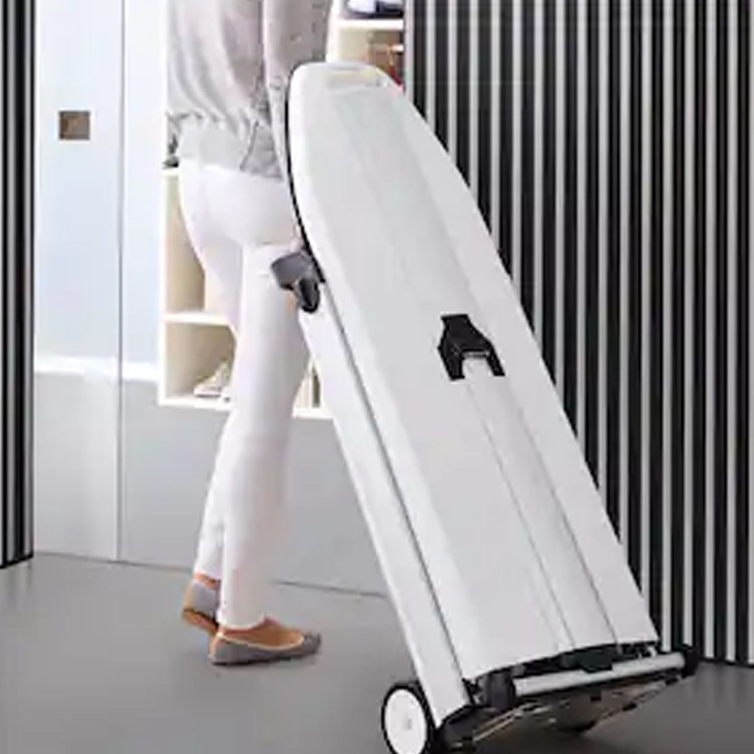 Woman pulling a white Fashion Master Steam Ironing System on wheels