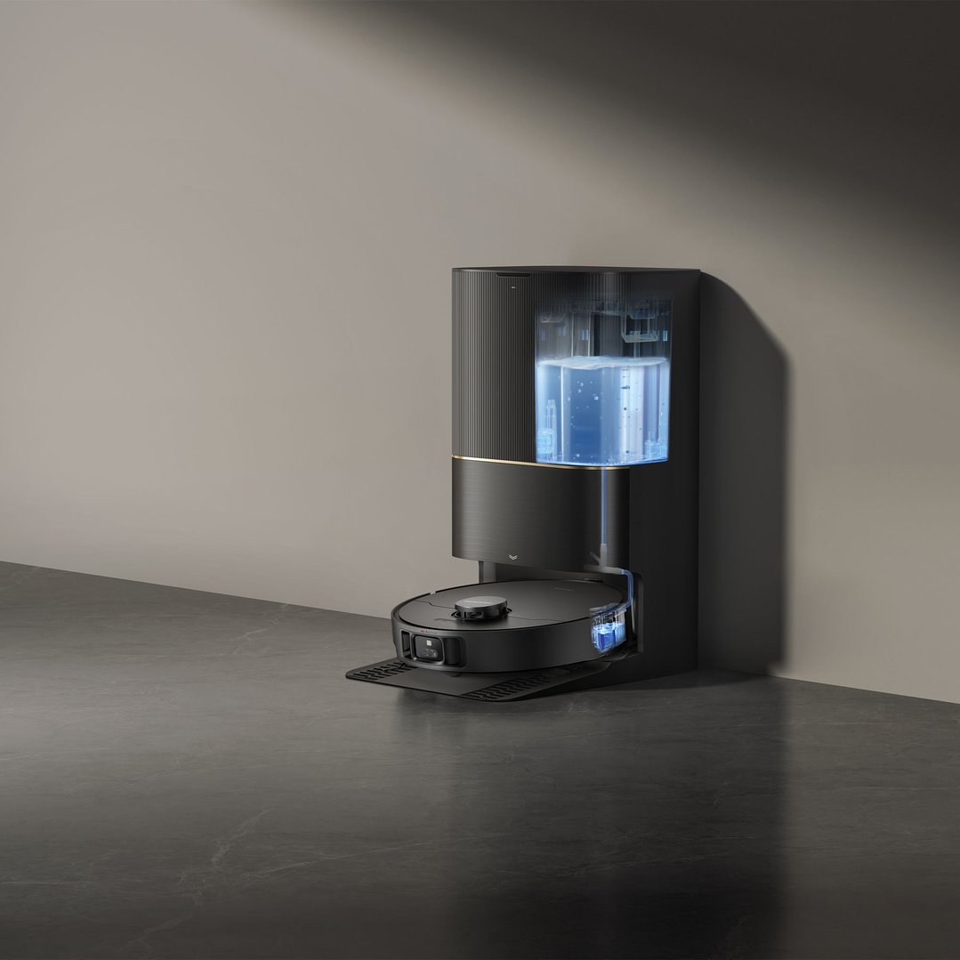 A black robot vacuum and mop with its self-cleaning station against a wall