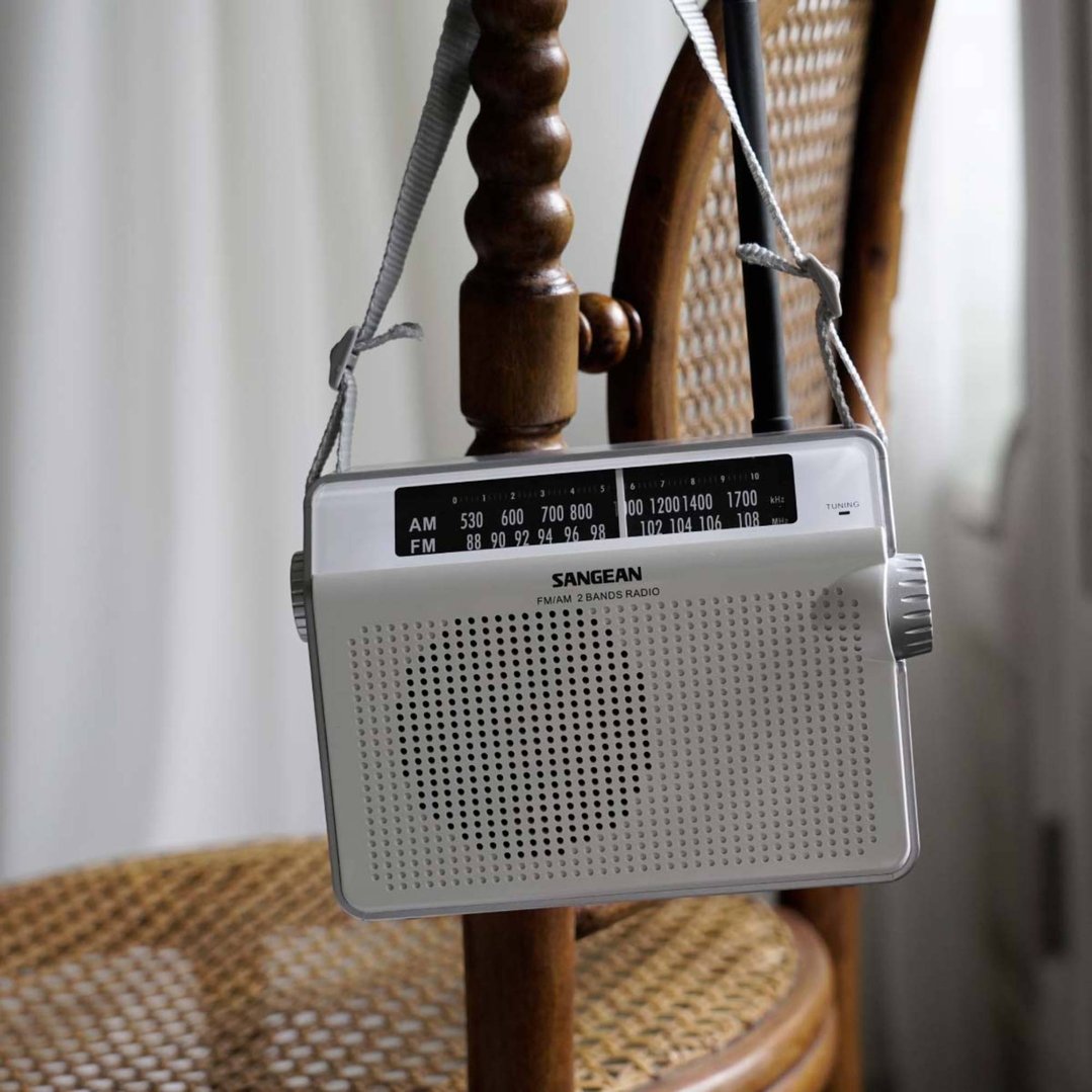 Portable radio hanging from a wooden chair in a room