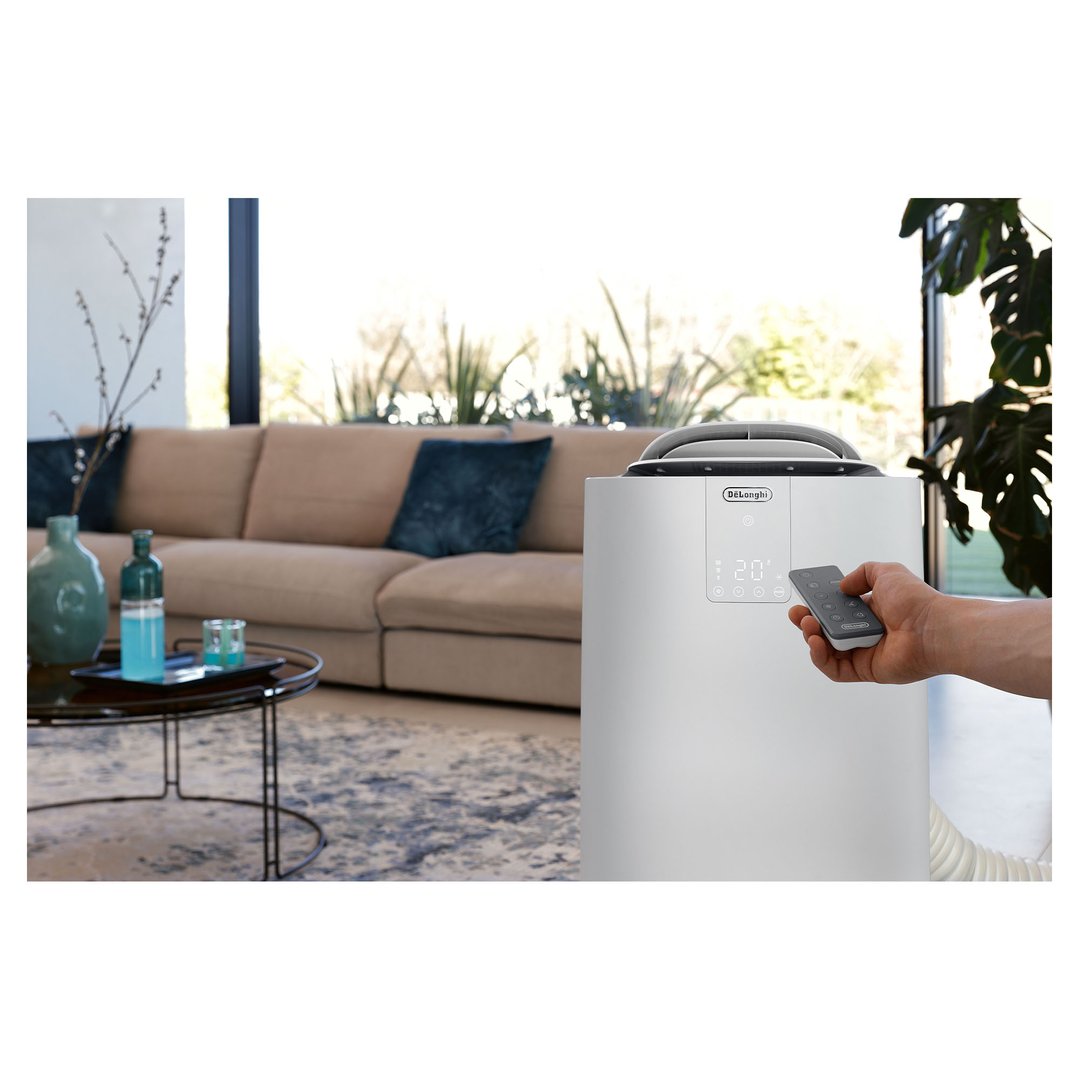 Hand holding remote control for a portable air conditioner in a living room