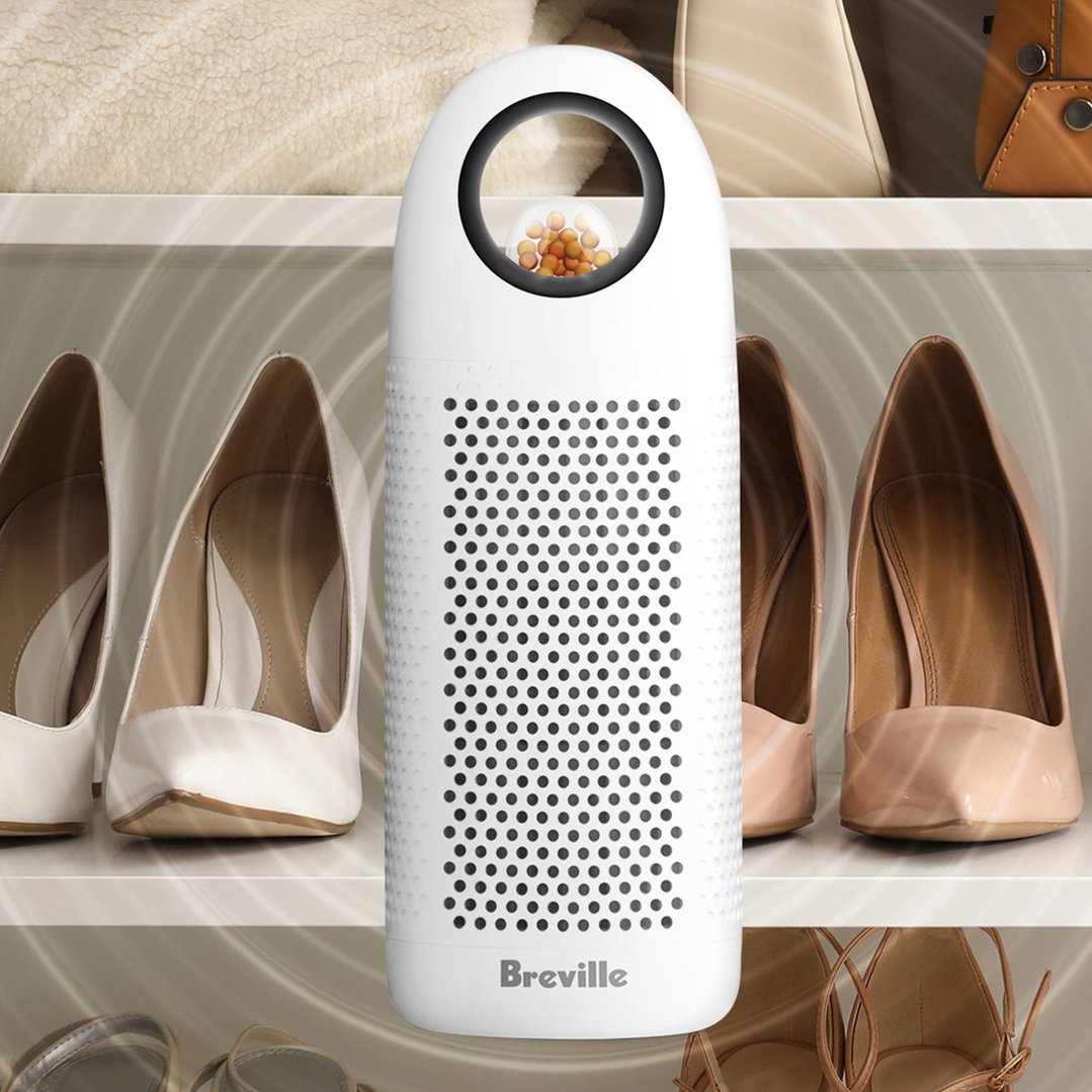 Breville dehumidifier standing on a shelf between pairs of shoes and bags