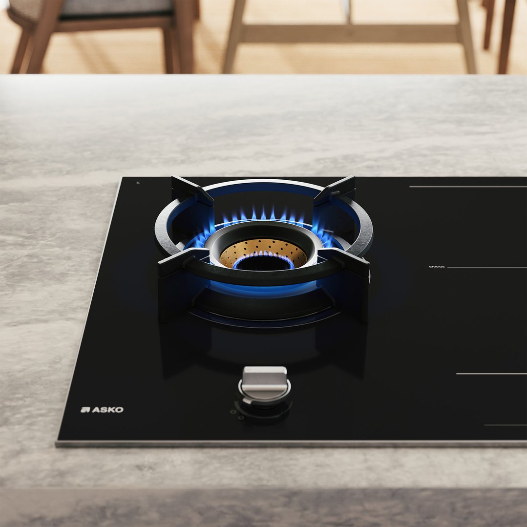 ASKO cooktop with gas burner lit on a grey countertop in a kitchen
