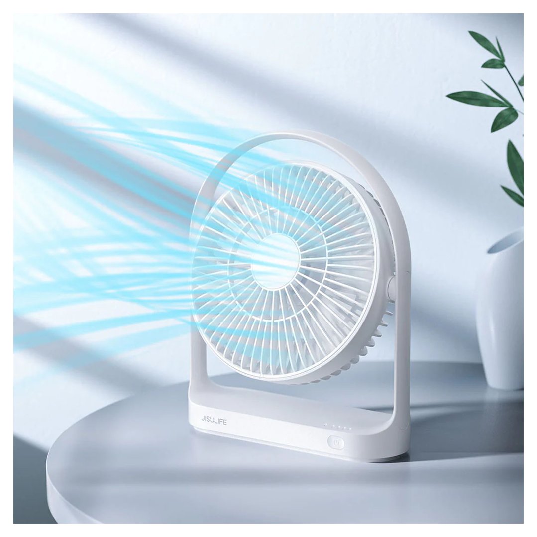 White JISULIFE table fan blowing air on a white table with a plant