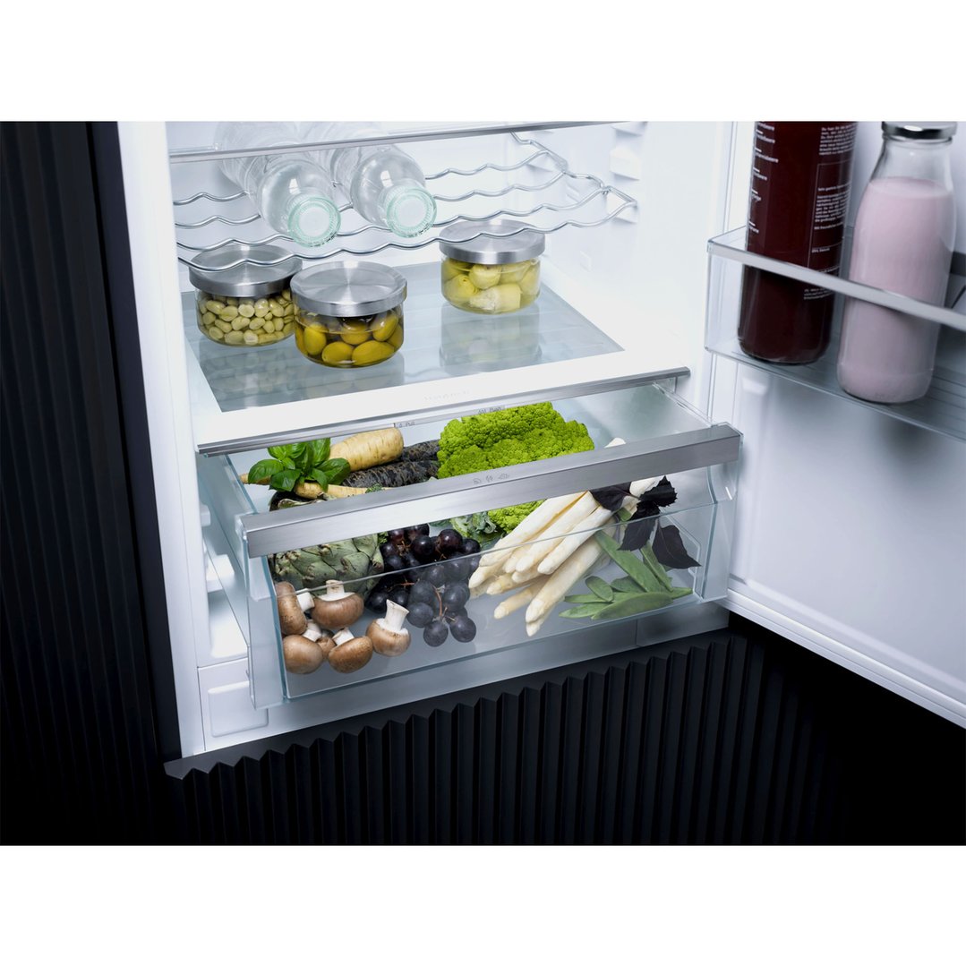 Open integrated bottom mount fridge with various foods and drinks inside