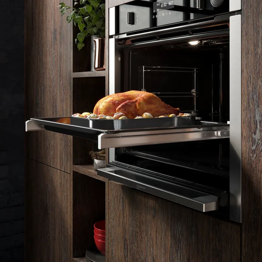 Built-in oven with a roasted chicken and vegetables on a pull-out tray