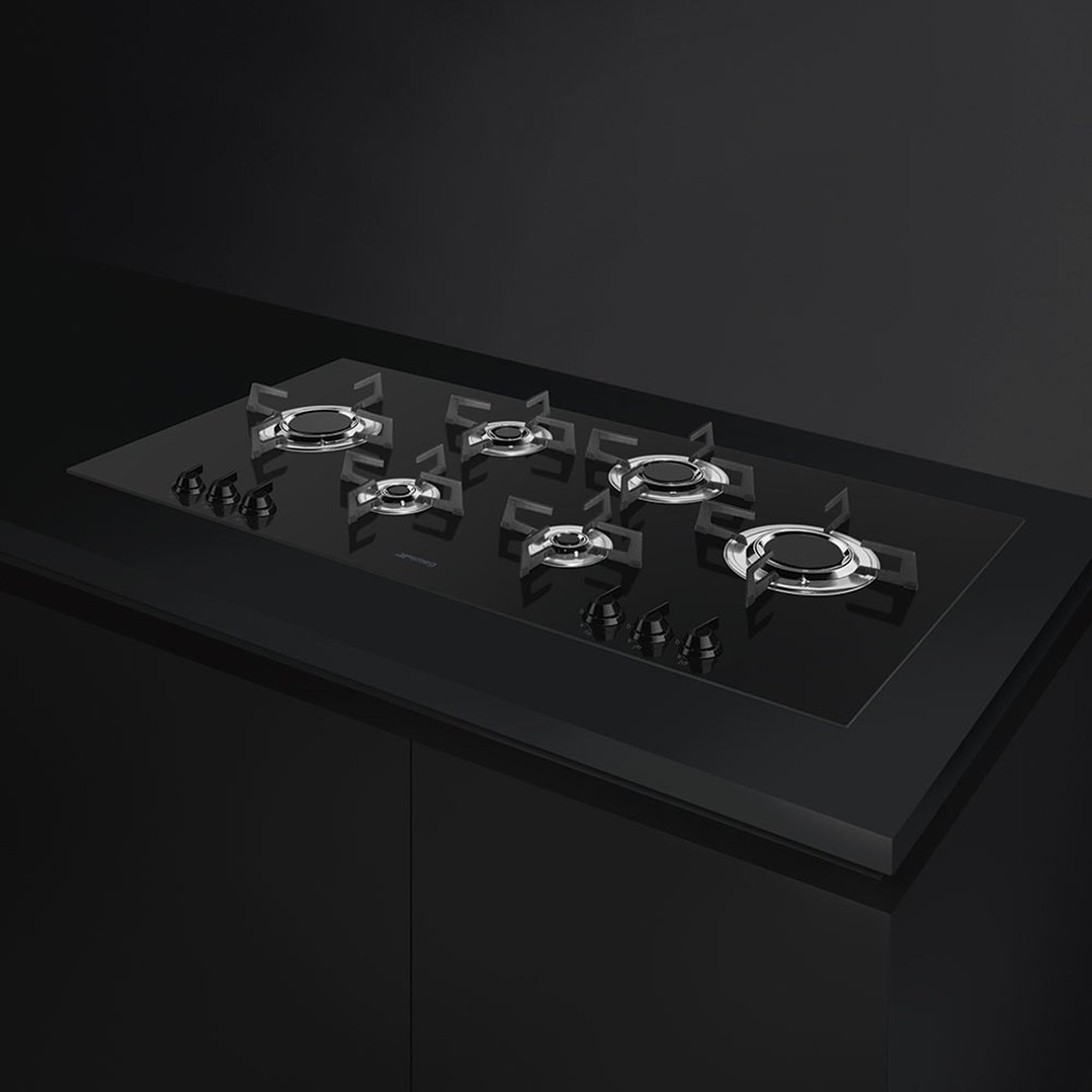 Black gas cooktop with five burners and controls, built into a dark countertop