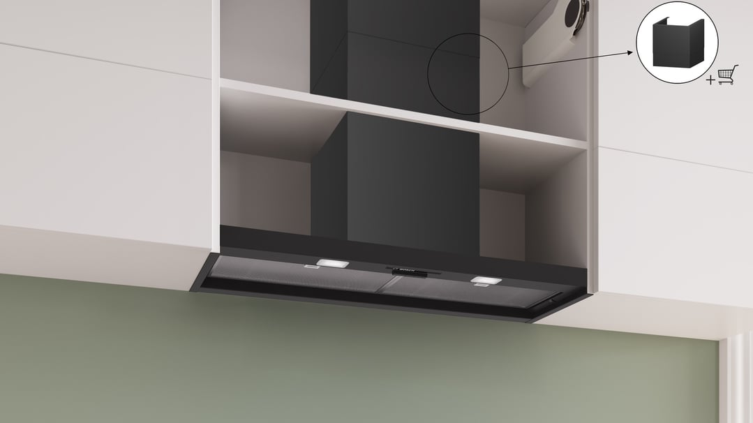 Black integrated rangehood installed under white kitchen cabinets with green wall