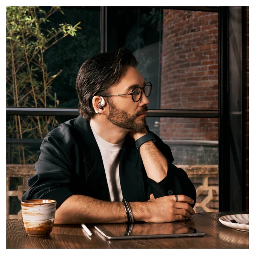Man wearing OpenFit Pro Wireless Open-Ear Headphones, sitting at a table