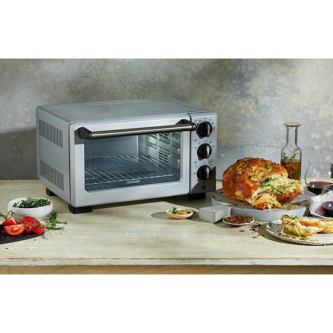 Sunbeam 18L Bake & Grill Oven on a wooden table with food and drinks