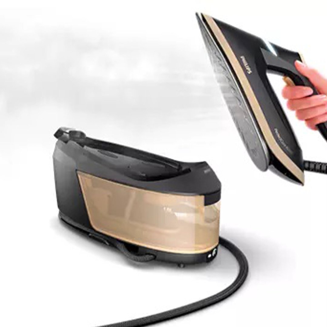 Hand holding a Philips steam generator iron above its base unit