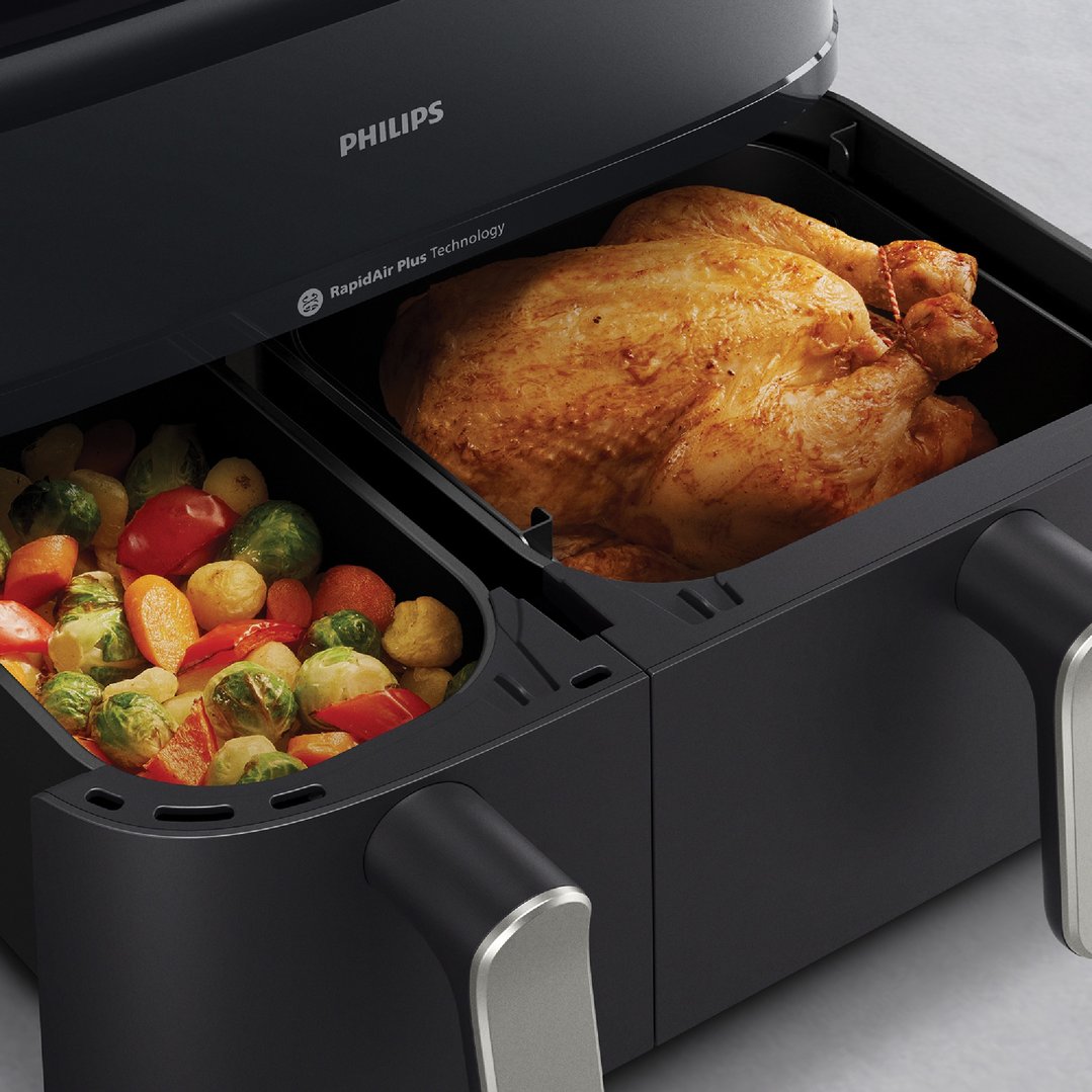 Philips deep fryer with a whole chicken and vegetables in its two baskets