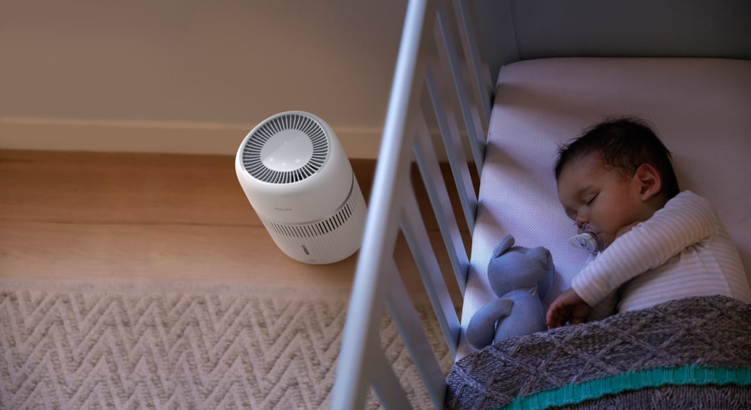 Air humidifier on the floor next to a baby sleeping in a crib