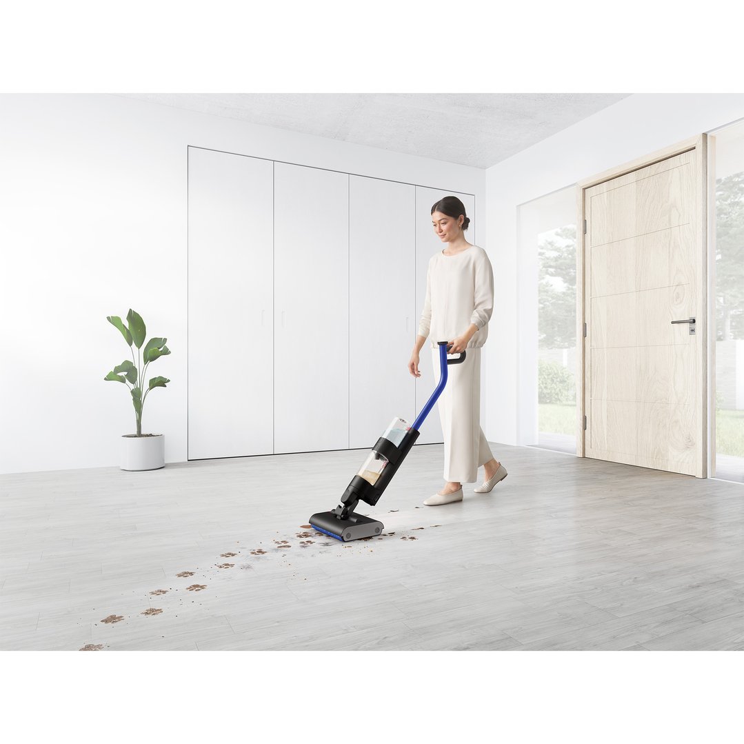 Woman using a Dyson WashG1 Wet Cleaner to clean paw prints on a light floor