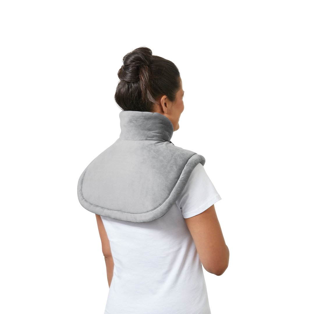 Woman wearing a gray heating pad on her shoulders and neck