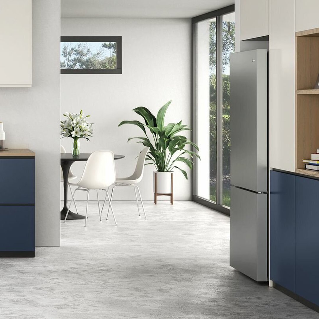 Bottom mount refrigerator in a modern kitchen with blue cabinets and dining area
