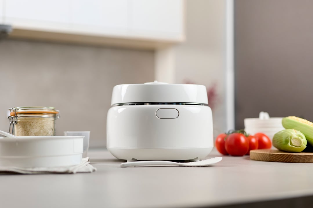 White rice and multi cooker on a kitchen counter with vegetables and rice