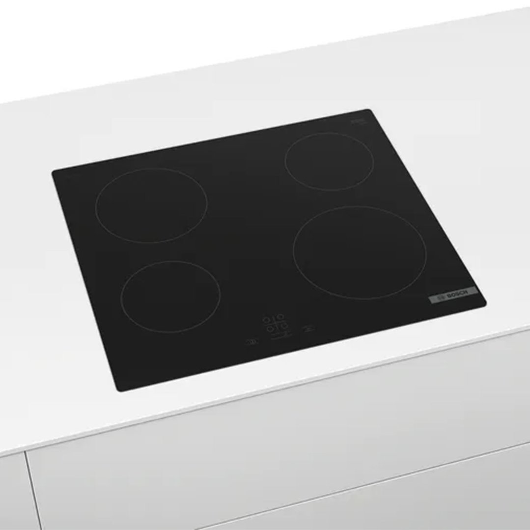 Black electric cooktop with four burners on a white kitchen counter