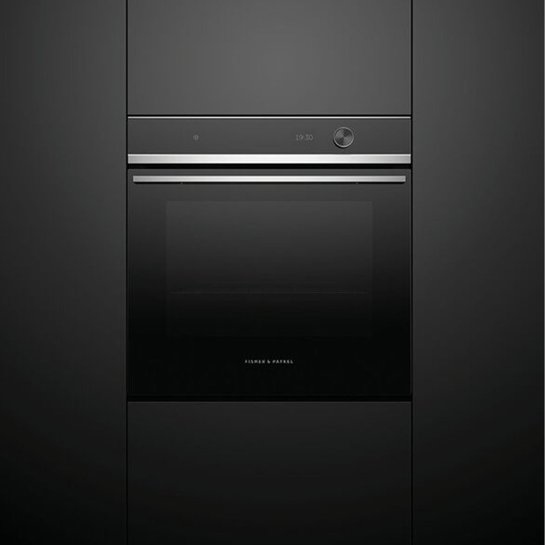Black built-in oven with a digital display and control knob in a dark kitchen