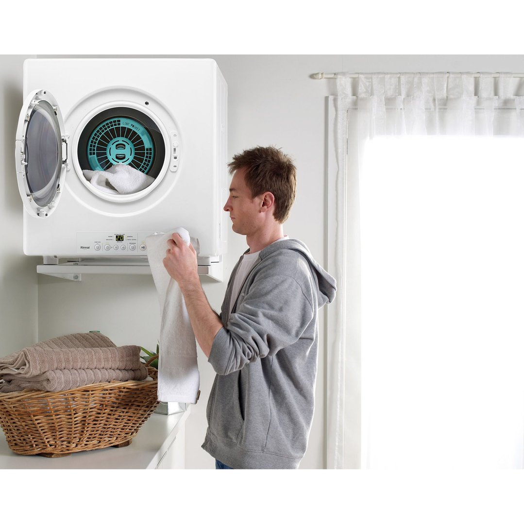 Man loading a white Rinnai dryer with a white towel in a laundry room