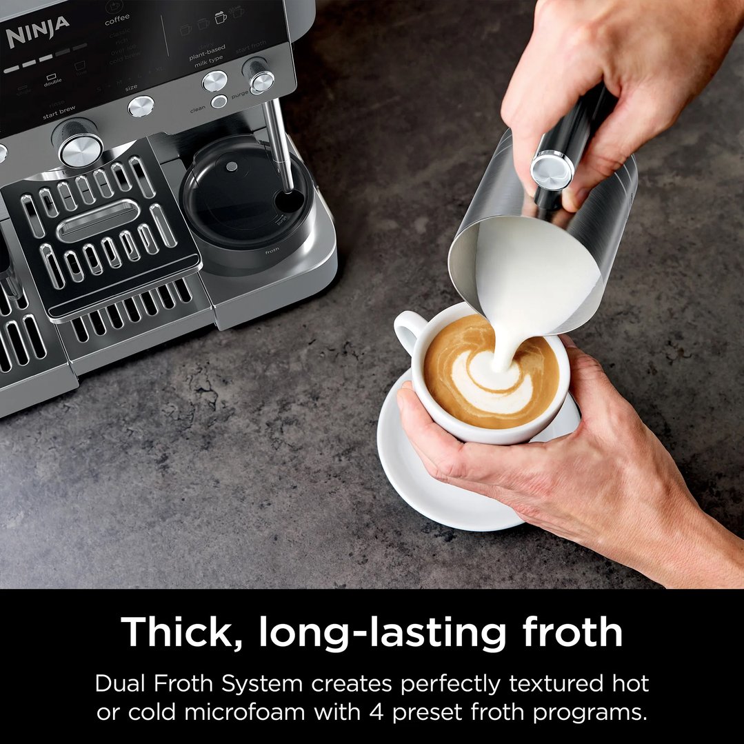 Hand pouring frothed milk from a pitcher into a cup of coffee