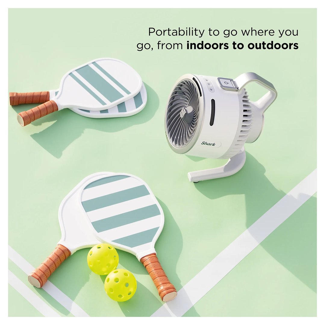 Portable fan on a green surface with pickleball paddles and balls