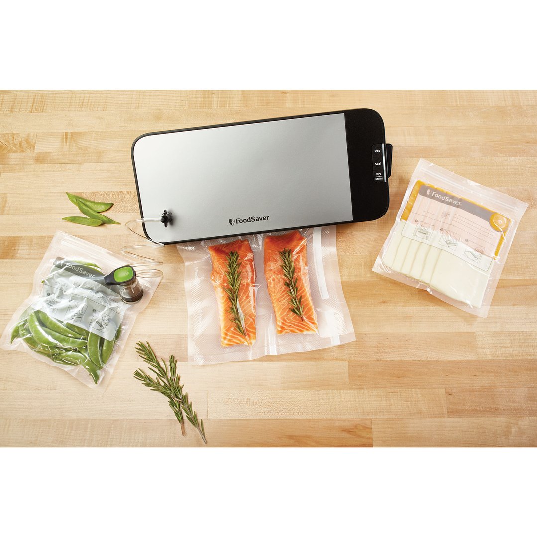 FoodSaver vacuum sealer with salmon, cheese, and peas on a wooden countertop