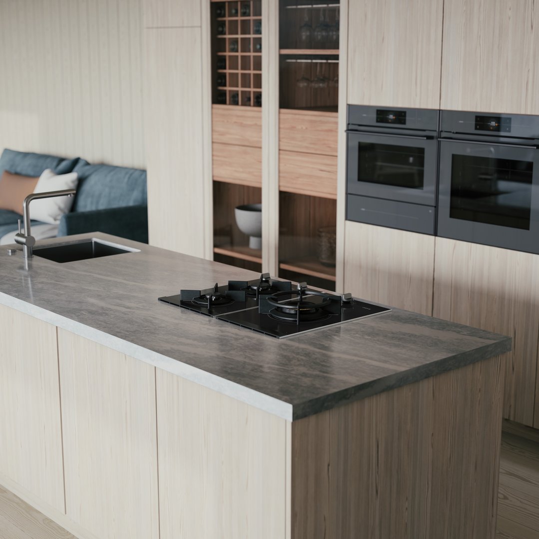 Black gas cooktop on a kitchen island with sink and ovens in background