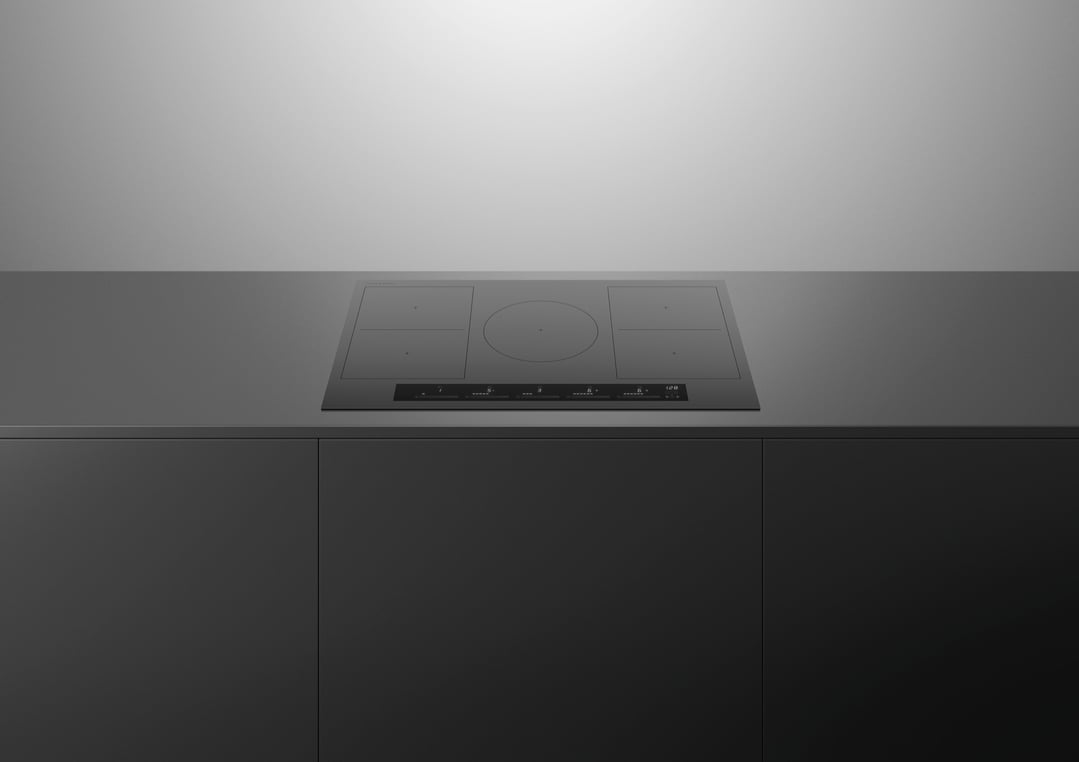 A black induction cooktop built into a dark grey kitchen countertop