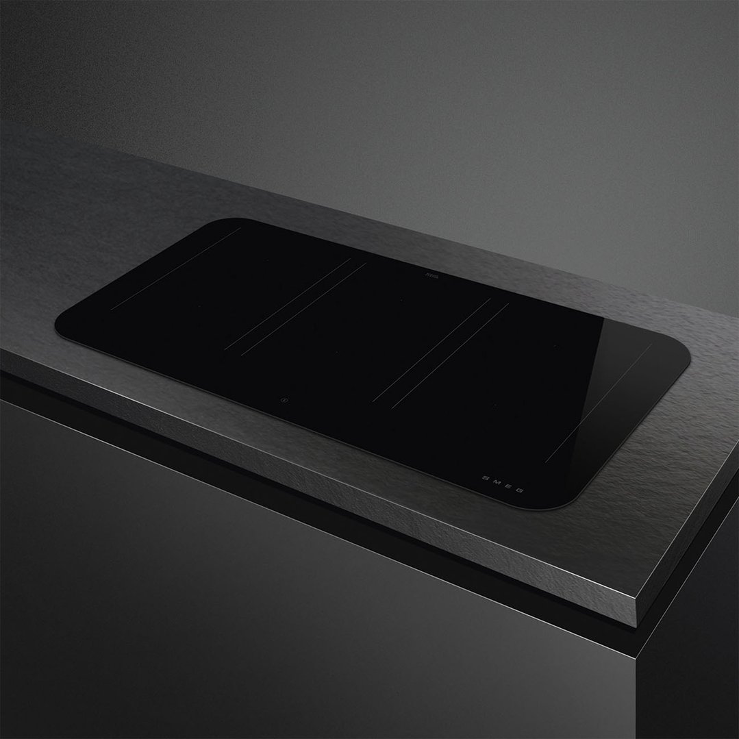 Black induction cooktop built into a dark countertop in a modern kitchen