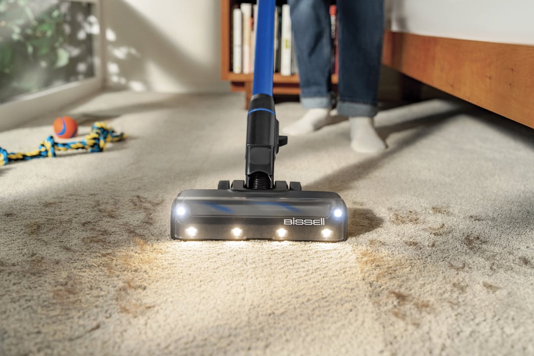 BISSELL handStickVacuum with illuminated head cleaning a dirty carpet
