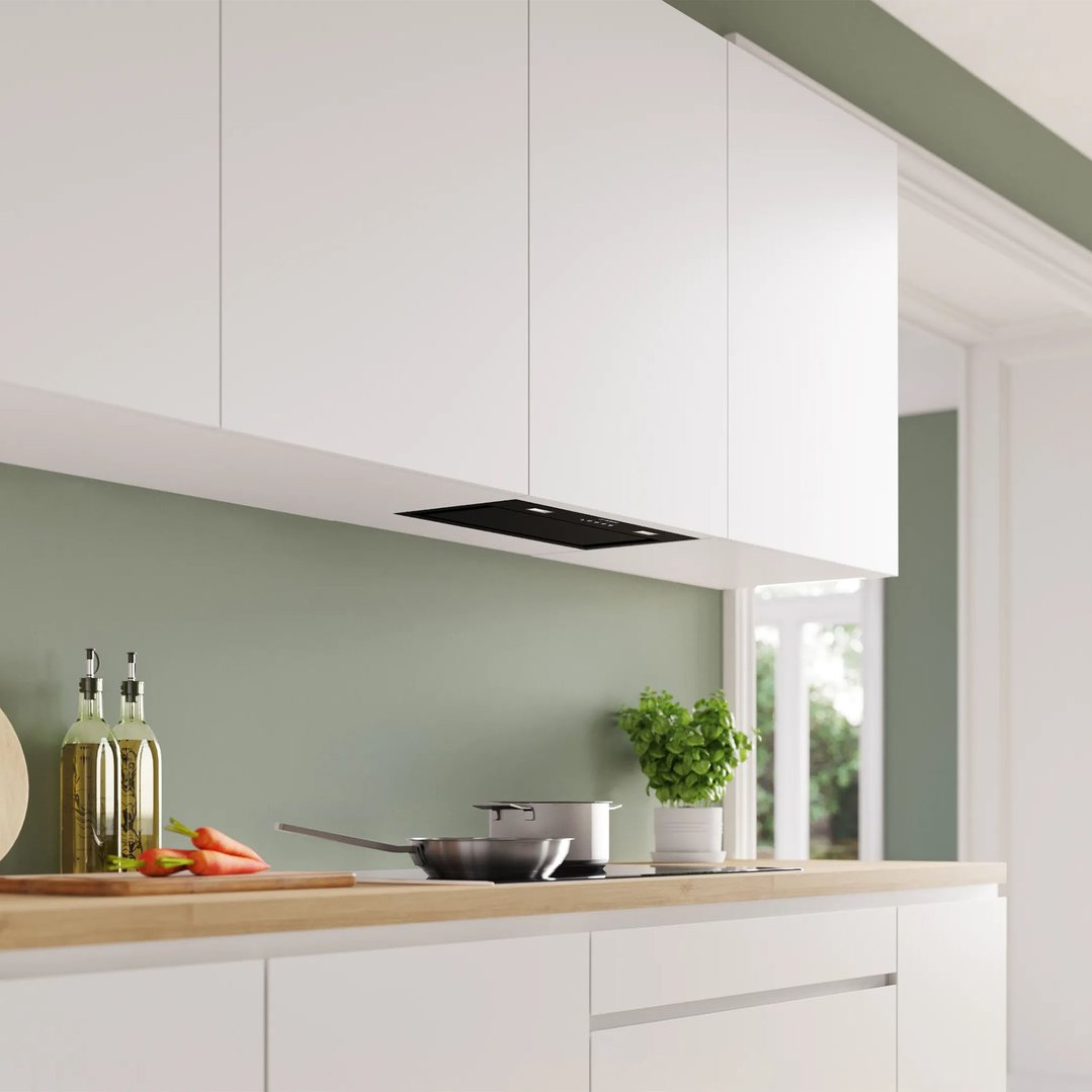 Integrated rangehood in a modern kitchen with white cabinets and green walls