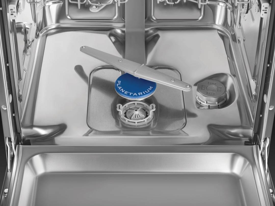 Inside view of a dishwasher showing the bottom rack area and spray arm
