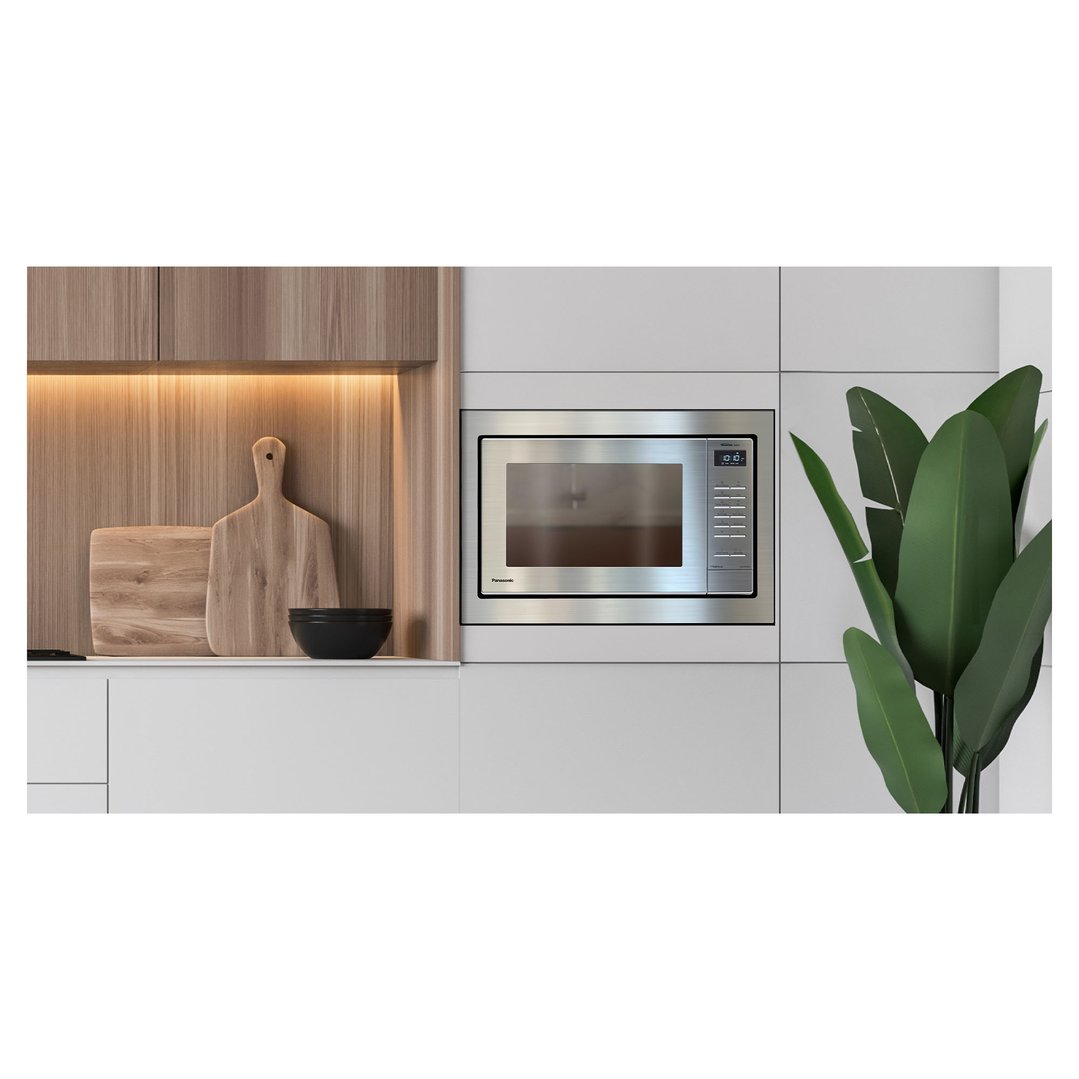 Stainless steel microwave built into white kitchen cabinetry with wooden accents