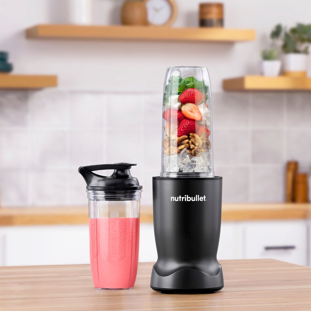 Black NUTRiBULLET blender with ingredients and a pink smoothie on a wooden counter