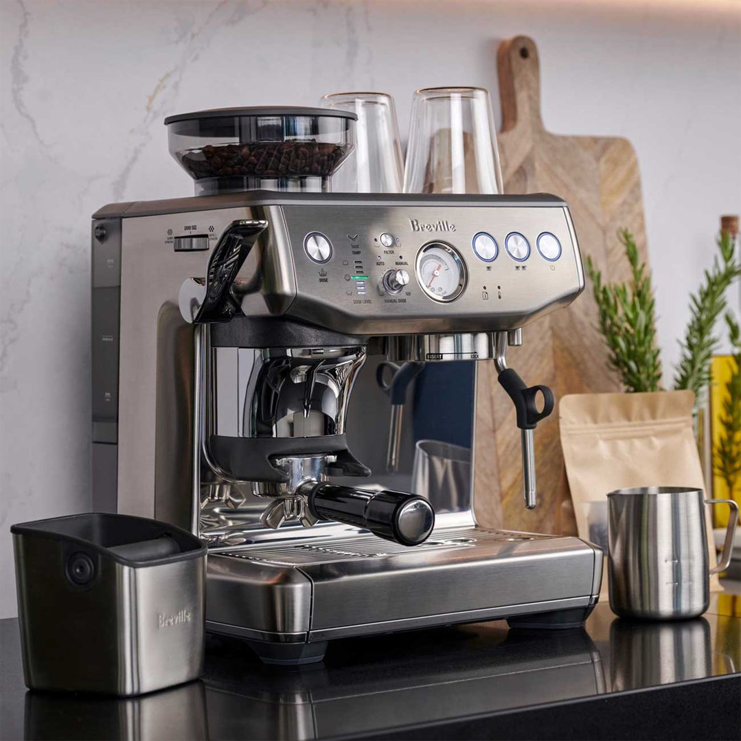 Breville Barista Express Impress coffee machine on a black countertop with accessories