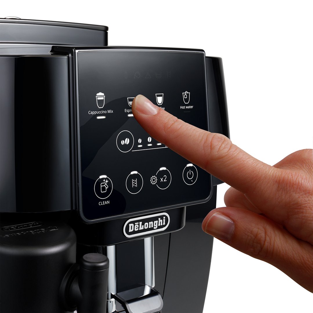 Hand pressing the espresso button on a black automatic coffee machine