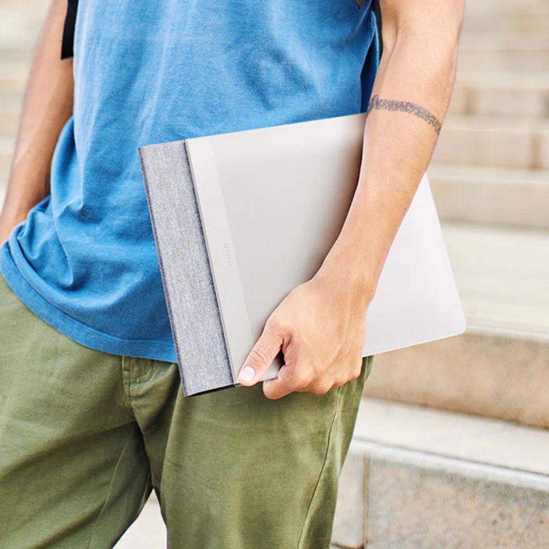 Person holding a grey laptop sleeve while standing on stairs outdoors