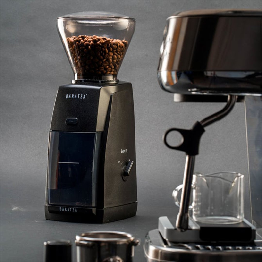 Encore ESP Coffee Grinder with coffee beans in hopper next to an espresso machine