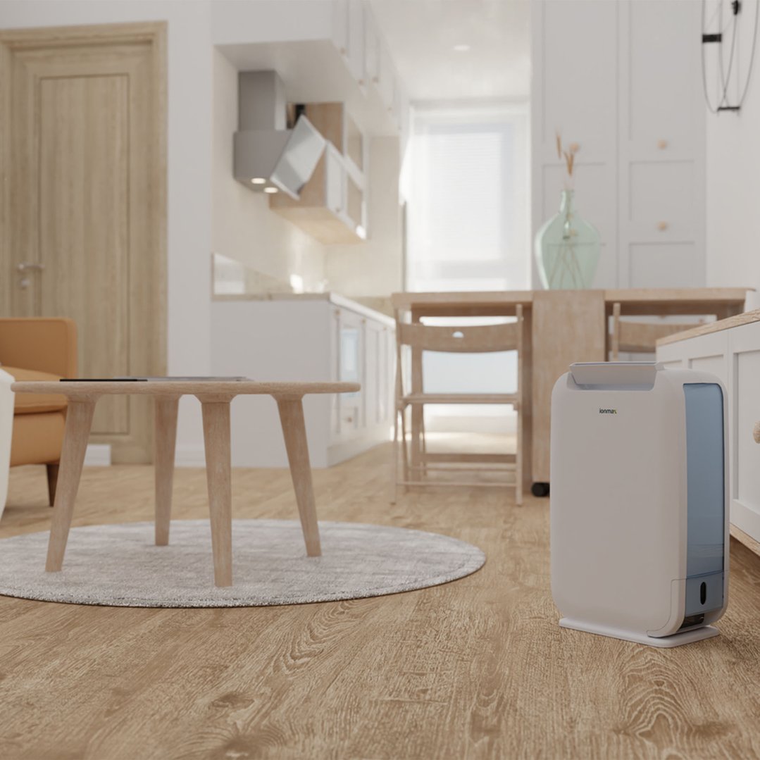 A white dehumidifier on a wooden floor in a modern living room and kitchen