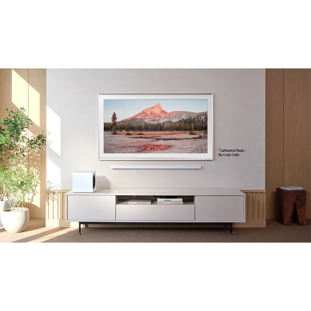 A TV displaying a landscape image, mounted above a white media console