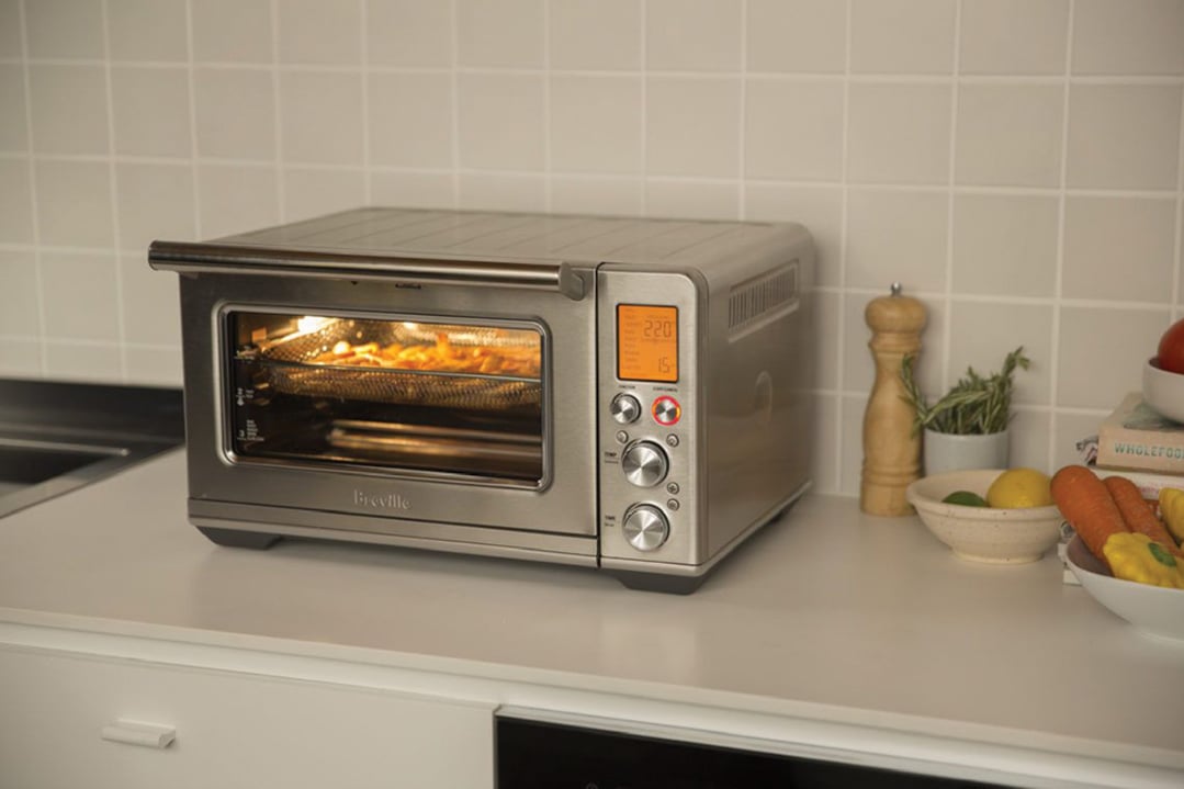 Breville Smart Oven Air Fryer on a kitchen counter with vegetables and spices