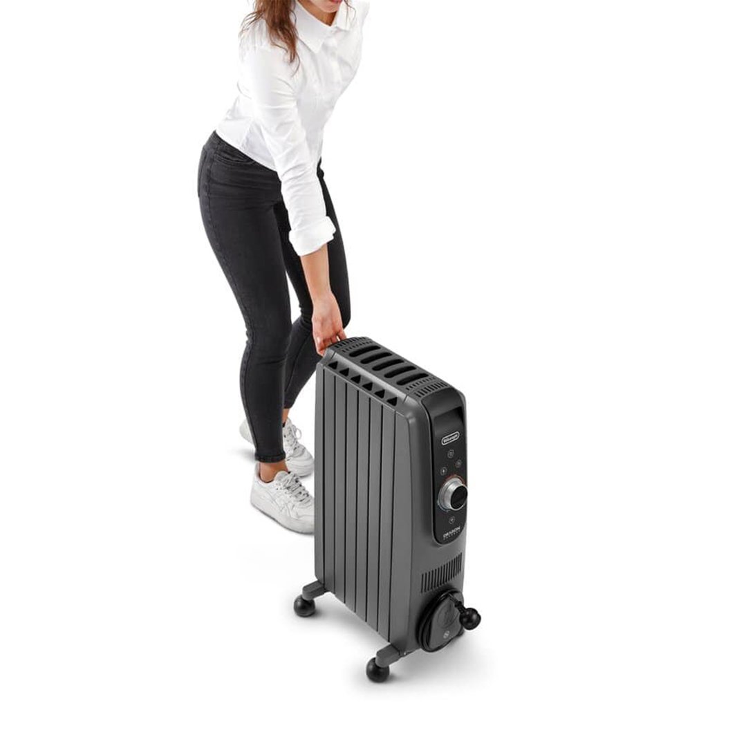 Woman in black jeans and white shirt moving a grey oil column heater