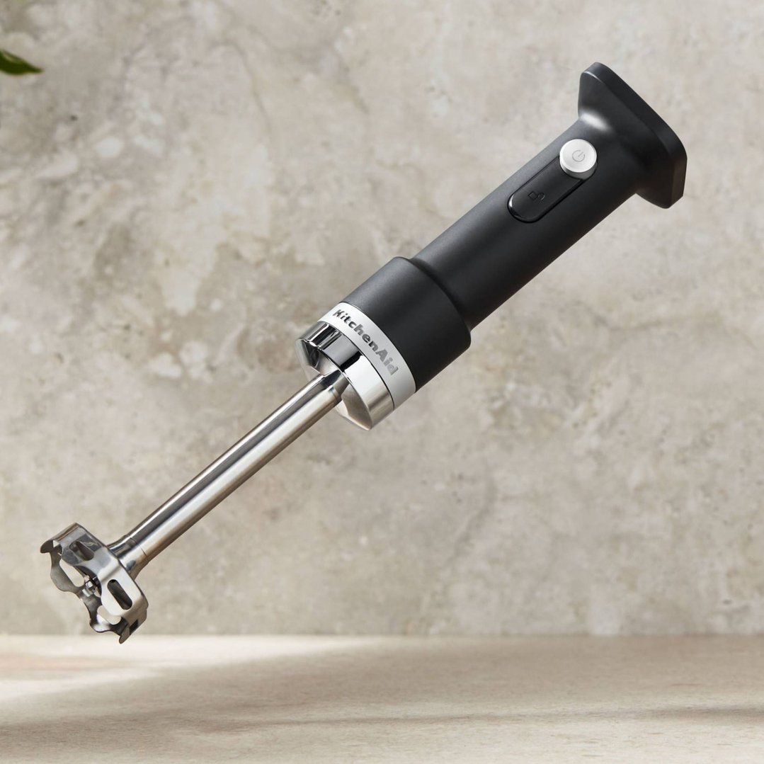 Black KitchenAid cordless hand blender with a stainless steel shaft on a light background