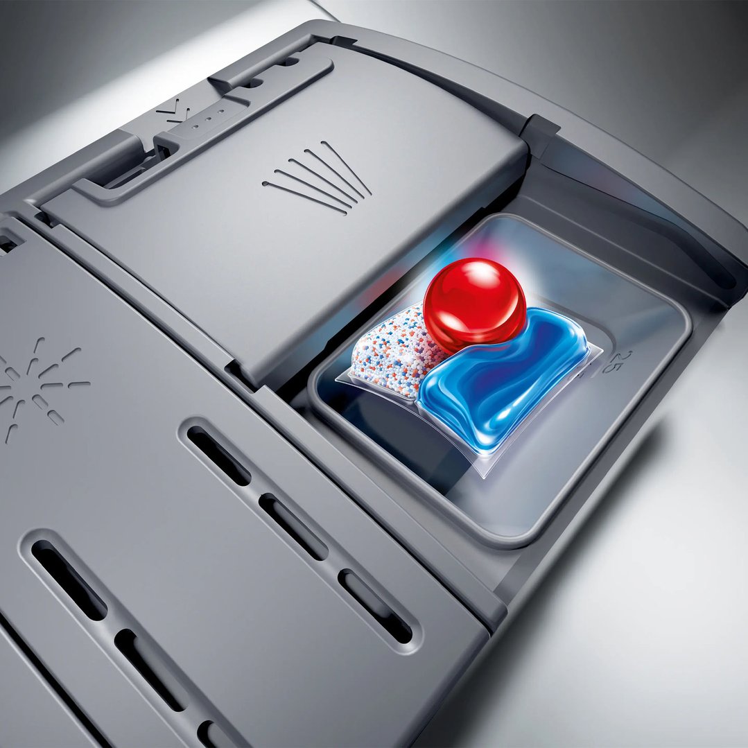 Close-up of a dishwasher dispenser with three different detergent pods inside