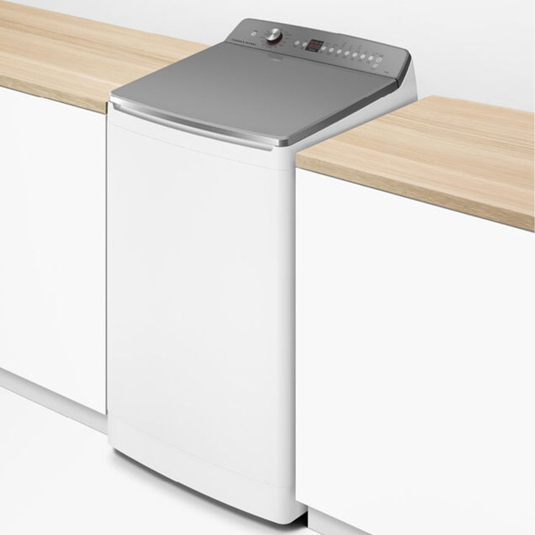 White top loader washing machine integrated into a light wood countertop
