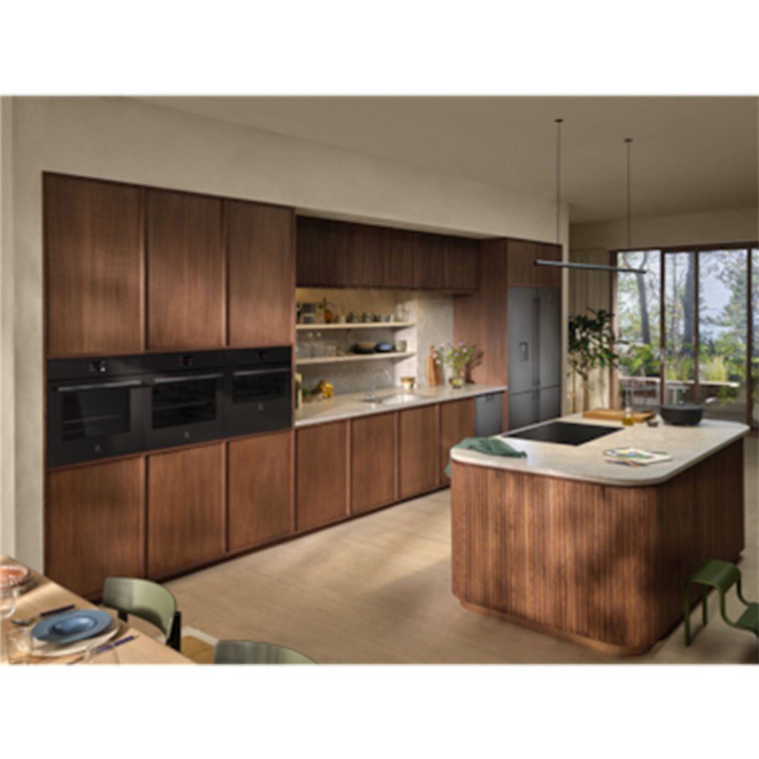 A modern kitchen with dark wood cabinets, three ovens, and an induction cooktop